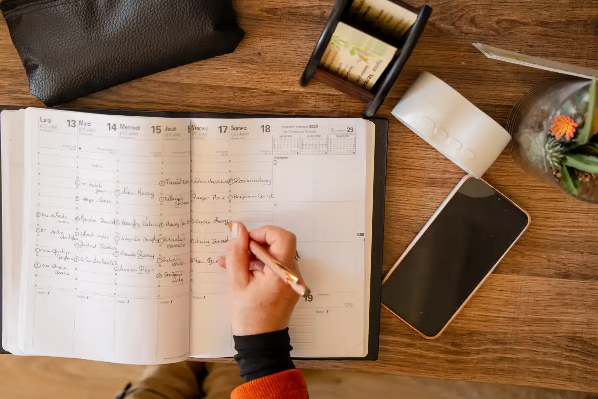 Mains posées sur une table avec un carnet et un stylo, ambiance calme et studieuse